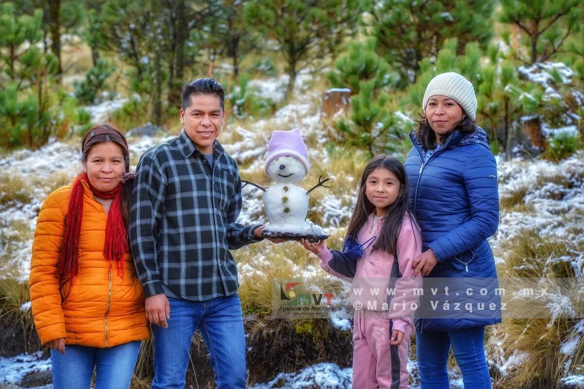 Integrantes de una familia muestran el muñeco de nieve que hicieron en las zonas altas de Temoaya