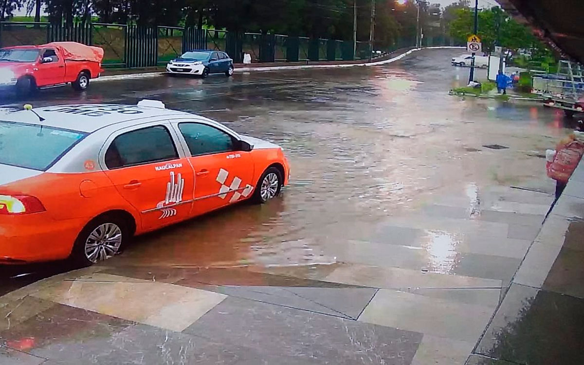 Avenida inundada sobre la autopista México-Toluca con una rejilla metálica en mal estado