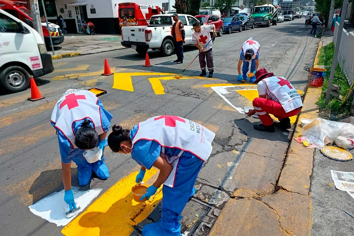 Voluntarios de la Cruz Roja señalizan calles en zonas escolares para prevenir siniestros viales.