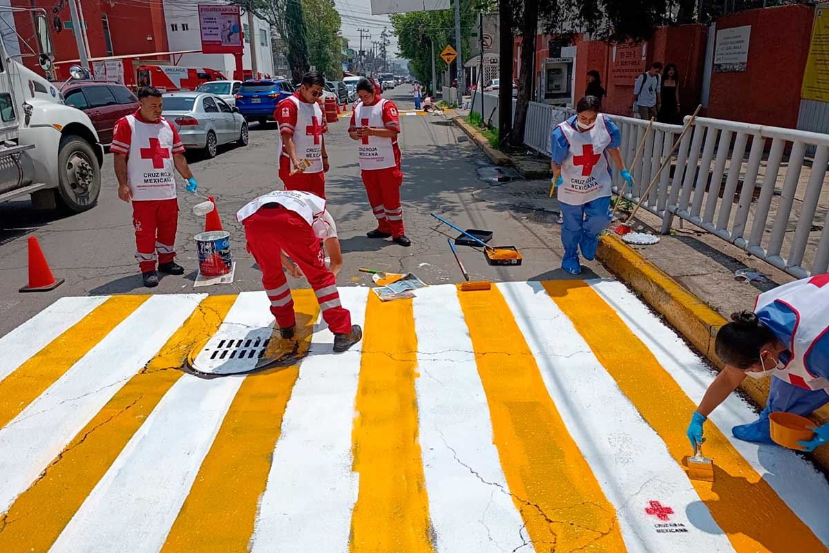 Voluntarios de la Cruz Roja señalizan calles en zonas escolares para prevenir siniestros viales.