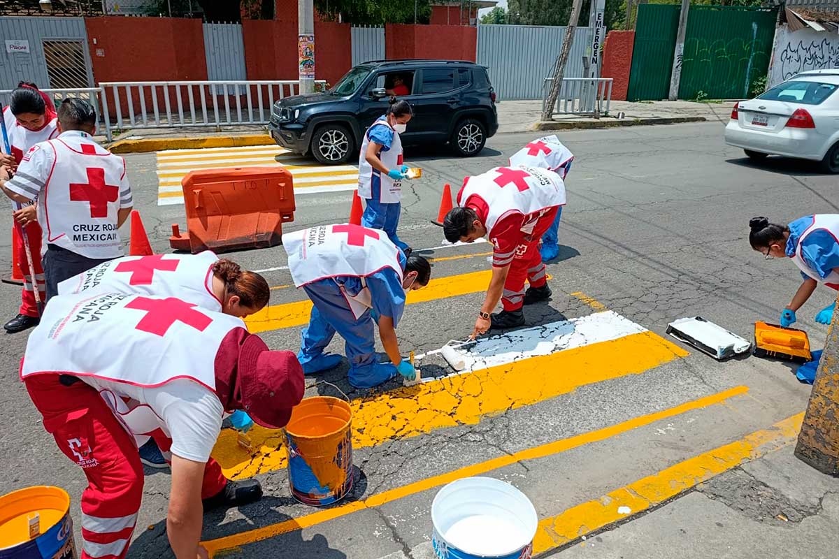 Voluntarios de la Cruz Roja señalizan calles en zonas escolares para prevenir siniestros viales.